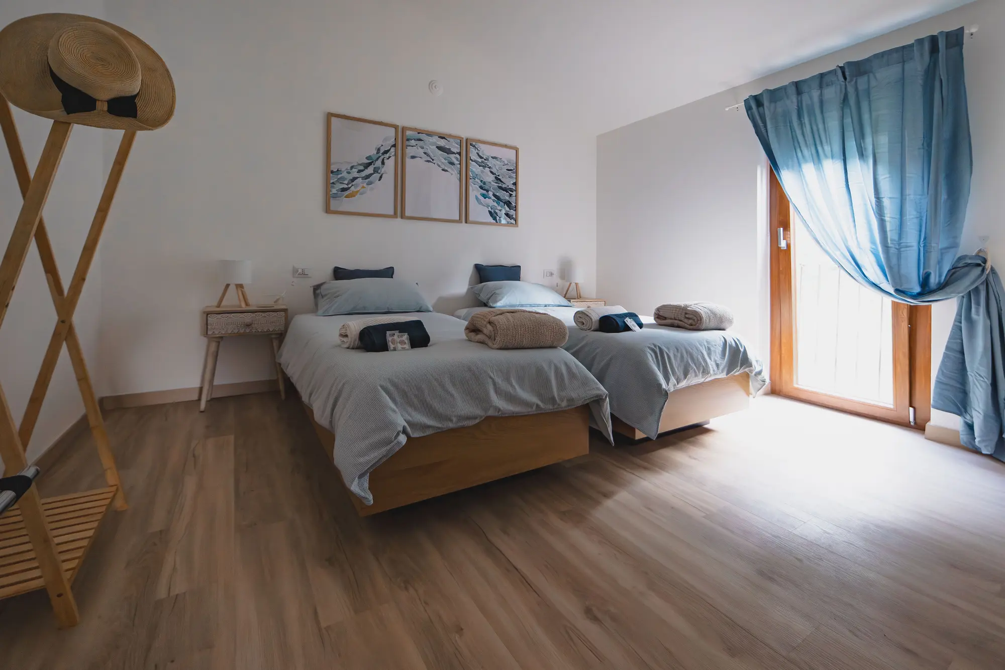 Bedroom with two single beds, wooden floors, and minimalist decor viewed from the hallway